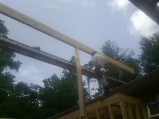 Carpenter setting a ridge beam over a new addition frame — Ice Dam Removal by Roofing Brothers in Magnolia