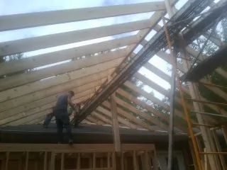 Rafters going up over a new addition with a worker on the wall in Magnolia