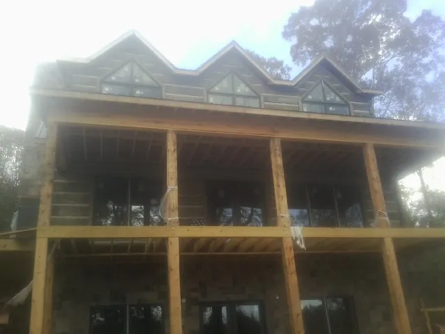 Dormers and porch framing on a large log home under construction — Roof Coating work by our crew in Magnolia
